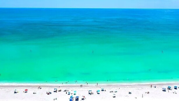 Een strand met helder turquoise water en een zandstrand.