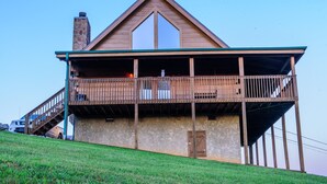 A two-story building with a balcony, a stone chimney, and a door. - Beautiful 2 bedroom 2 bath clean log cabin.  (Sevierville)