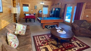 A cozy wooden cabin interior with a pool table, a sofa, a coffee table, and a ceiling fan. - Beautiful 2 bedroom 2 bath clean log cabin.  (Sevierville)