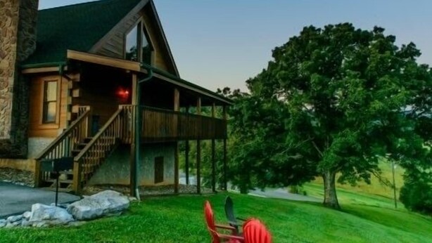 A two-story log cabin with a porch and a staircase leading to the upper level. - Beautiful 2 bedroom 2 bath clean log cabin.  (Sevierville)