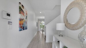 A hallway with a welcome sign, a thermostat, a painting, a mirror, a lamp, and a potted plant. - Resort Style, close to Disney and other parks Wlking Distance to Oasis Club (Davenport)