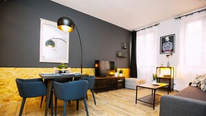 Un salon moderne avec coin repas, doté d’un parquet, de murs gris foncé et de meubles contemporains.