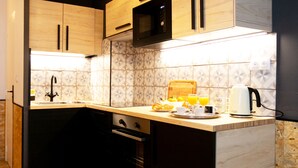 Une cuisine moderne avec des meubles en bois, un four à micro-ondes, un évier et un plan de travail agrémenté d’un panier de fruits et d’une bouilloire.