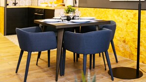 Une cuisine moderne avec un coin repas, comprenant une table en bois, quatre chaises et un lampadaire noir.