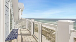 A balcony with a wooden deck, white railings, and a view of the beach and ocean. - "Soul Surfer" Dream Vacation Home w/ Direct Beach Access on the East End of Panama City Beach. Private Pool, Game Room, Large Suites + More! (Panama City Beach)