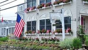 Un edificio con un cartel de 'VACANCY', banderas estadounidenses y macetas con flores en las ventanas.
