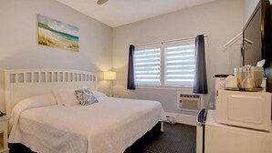 Una habitación de hotel con cama, televisión, microondas y ventana con cortinas.