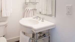 Un baño moderno con lavamanos blanco, grifería cromada y un espejo grande.
