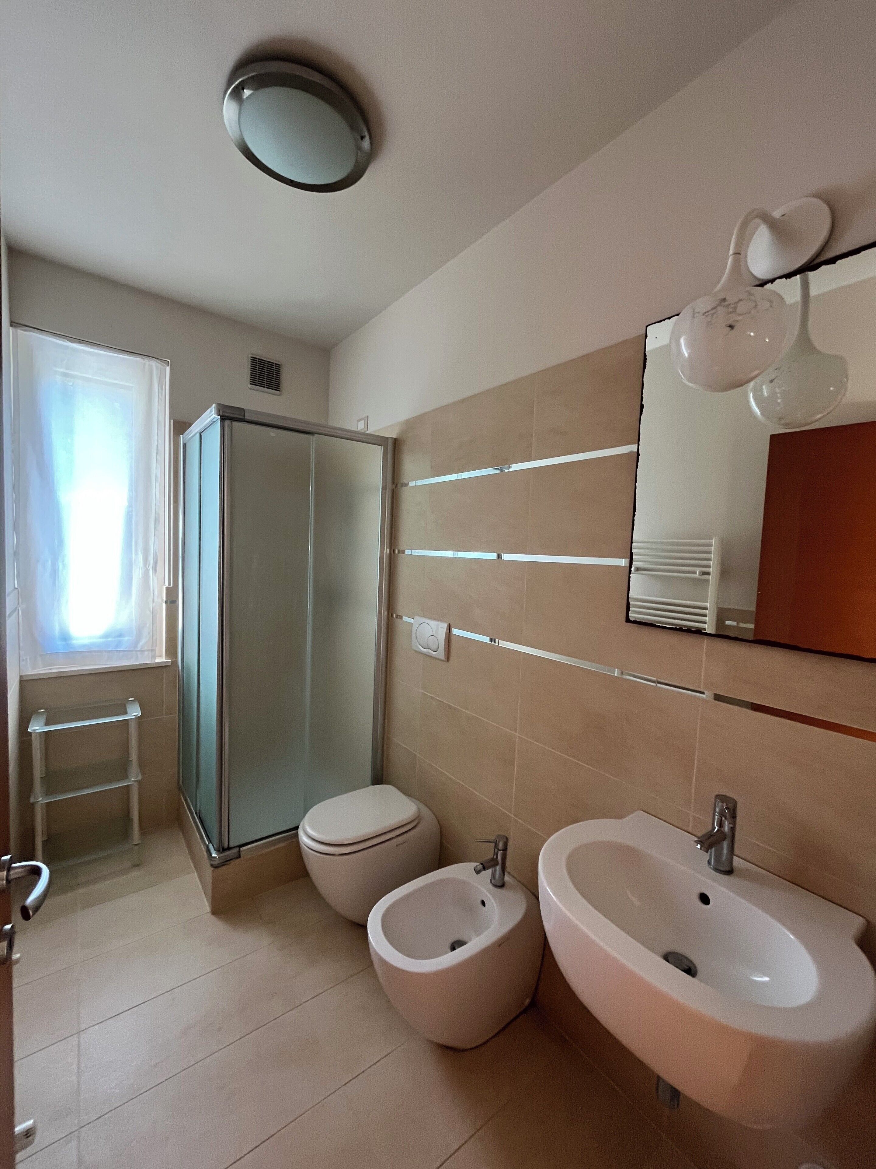 A bathroom with a shower, toilet, bidet, and sink.