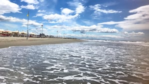 Una spiaggia con ombrelloni e una ruota panoramica sullo sfondo.