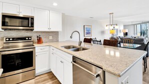 A modern kitchen with white cabinets, stainless steel appliances, and a granite countertop.