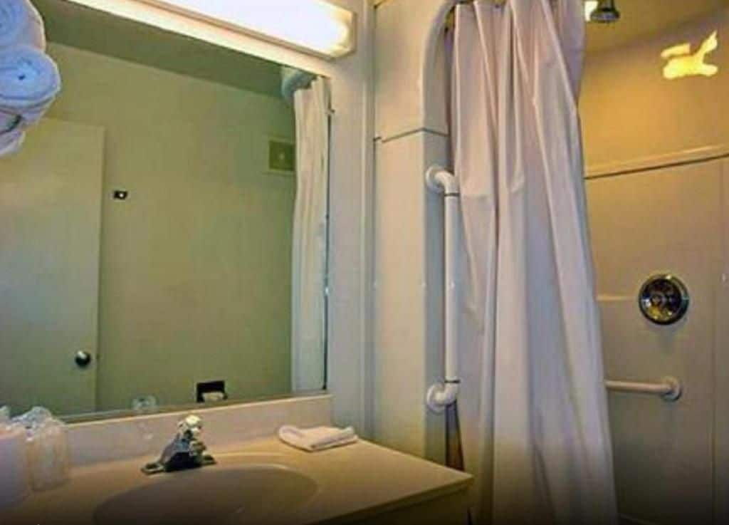 Een badkamer met een wastafel, spiegel en douchegordijn.