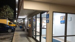 A parking area with a blue handicapped parking sign, a yellow van, and a blue car. - Studio 6 Wichita, KS - Airport (Wichita)
