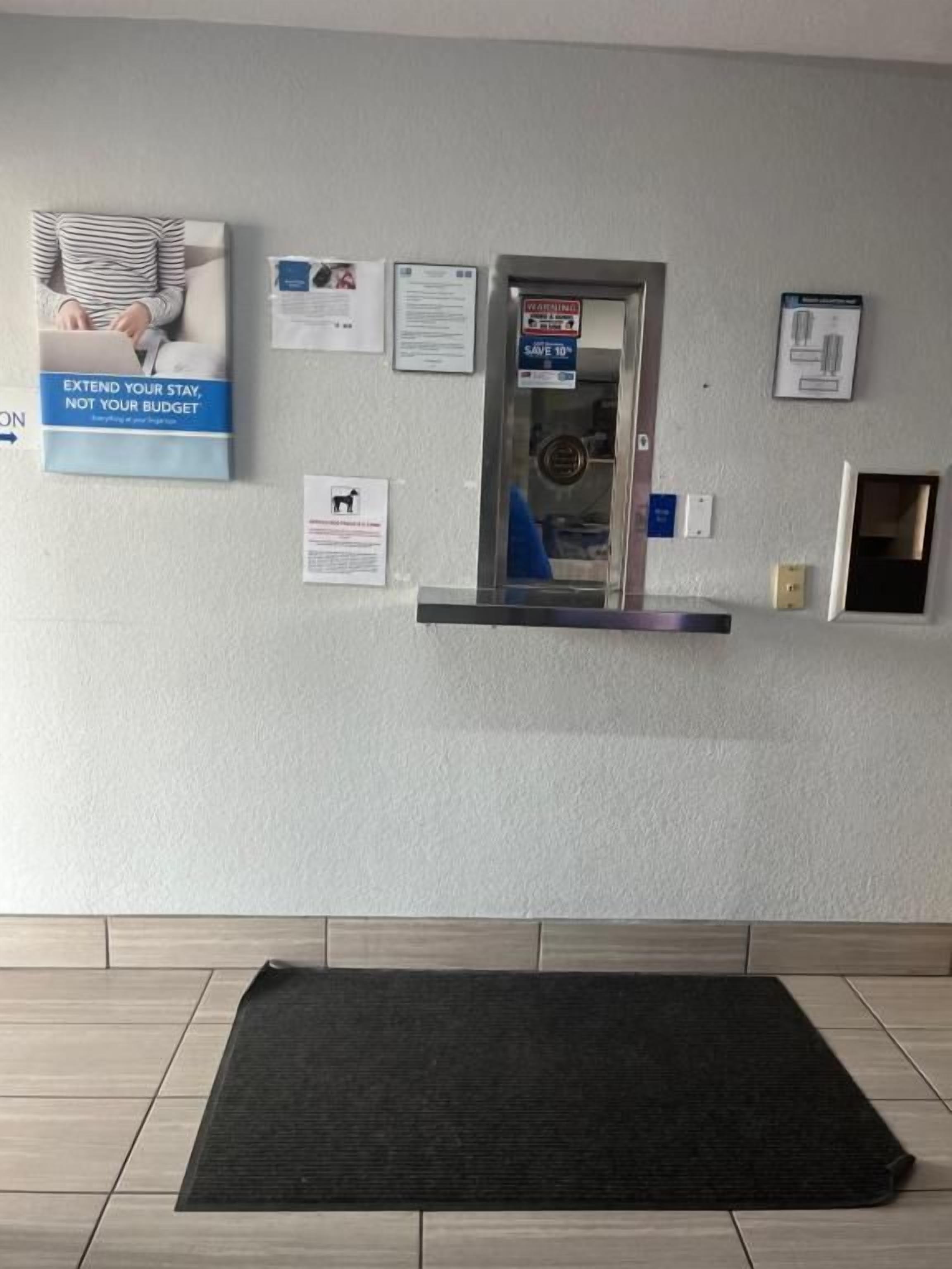 A reception area with a reception desk, a black mat, and various informational posters on the wall.