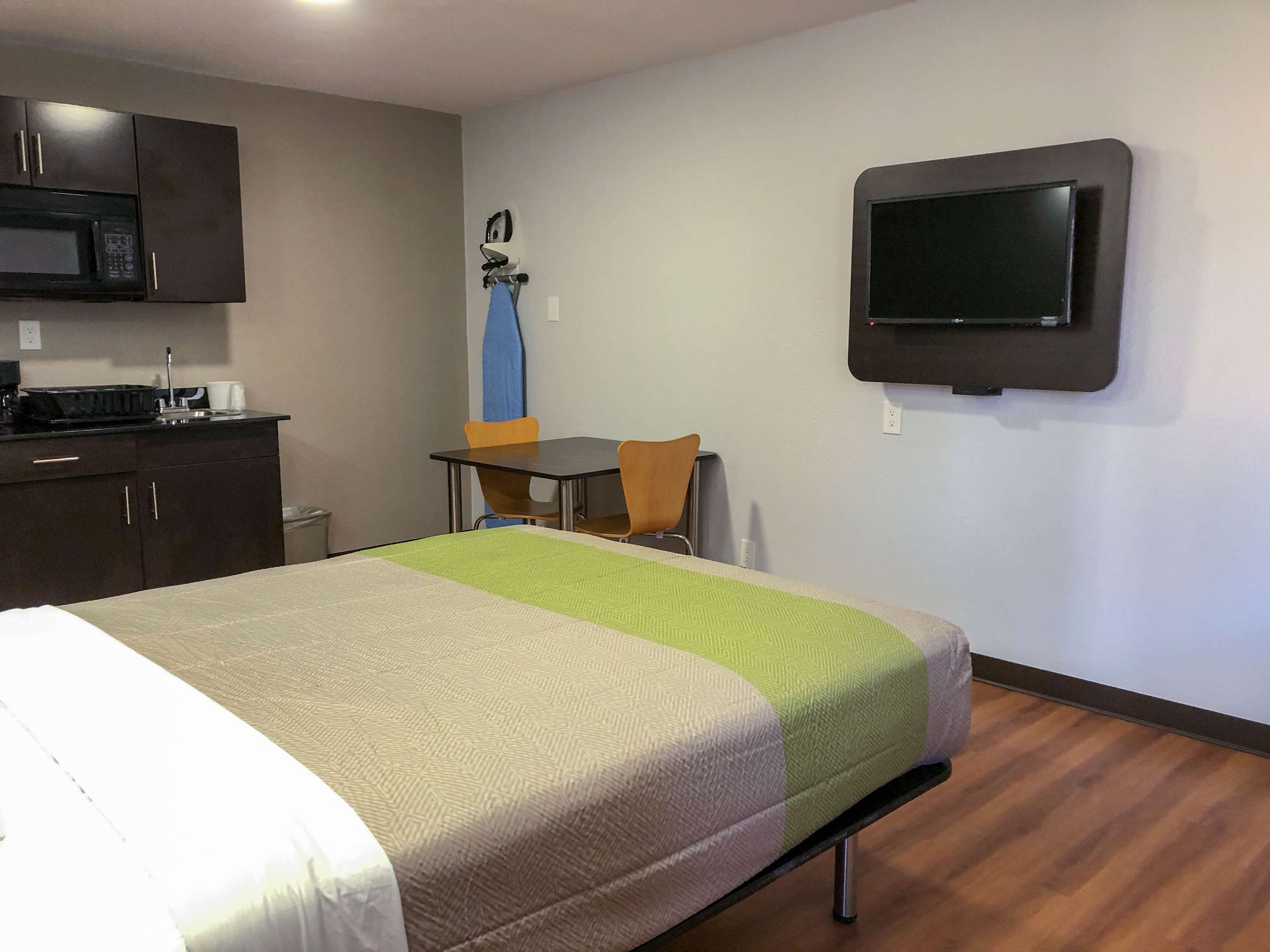 Een hotelkamer met een bed, een bureau, een stoel, een magnetron en een televisie.
