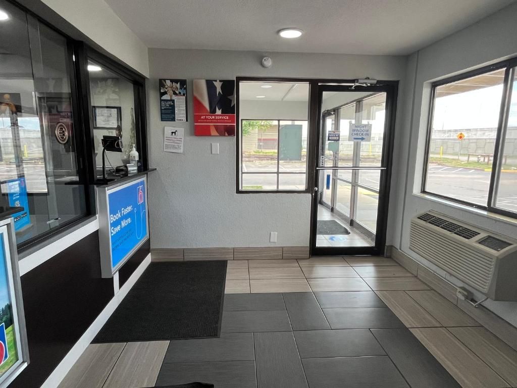 A reception area with a glass door leading outside, a reception desk, and a sign indicating a night window check-in.