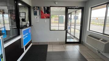 A reception area with a glass door leading outside, a reception desk, and a sign indicating a night window check-in.