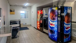 A room with a glass table, chairs, a refrigerator, and two Pepsi vending machines. - Studio 6 Wichita, KS - Airport (Wichita)