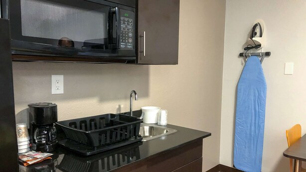 A compact kitchen with a black microwave, a sink, and a coffee maker. - Studio 6 Wichita, KS - Airport (Wichita)