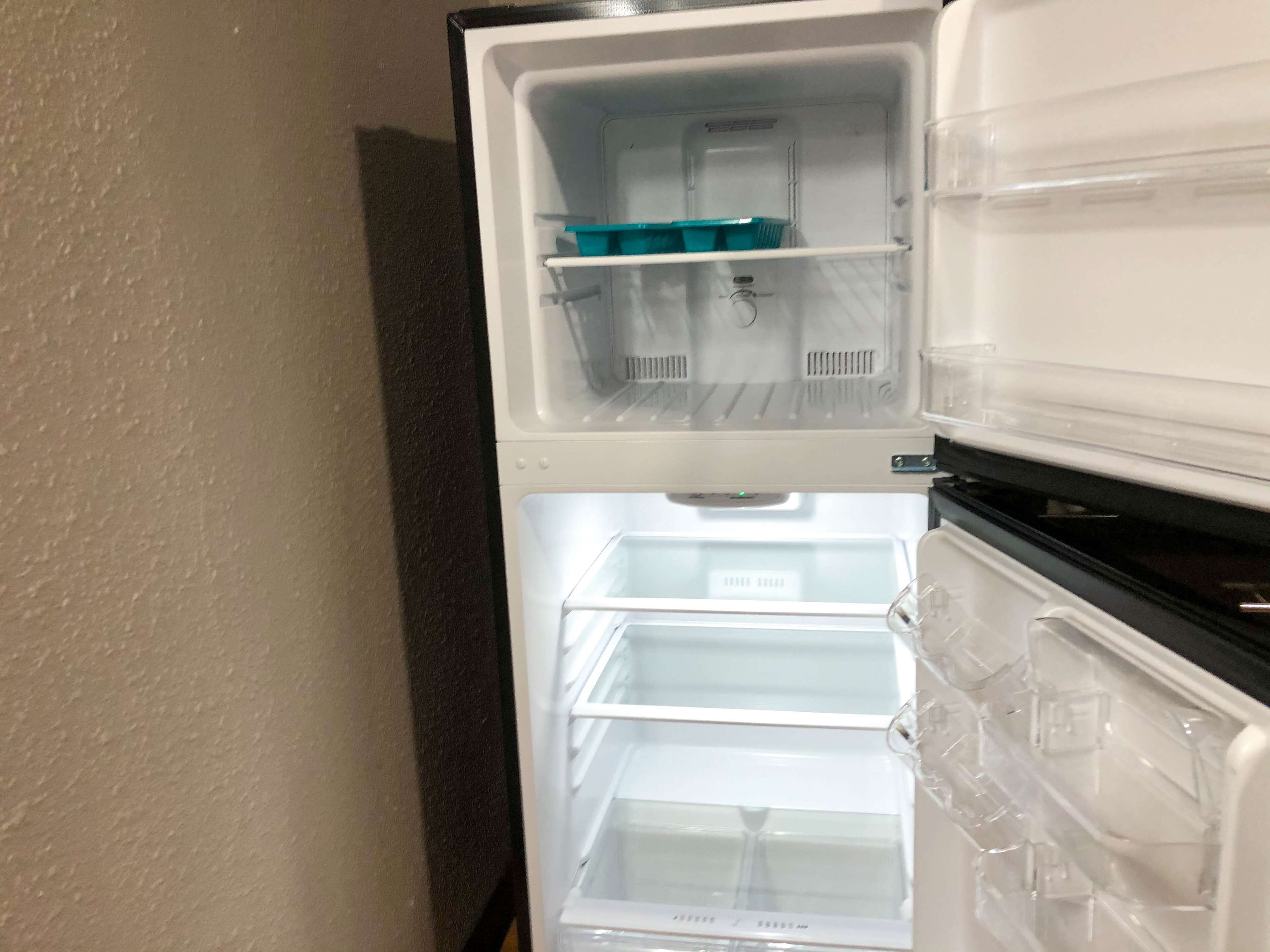 Un refrigerador con dos compartimentos, uno con una bandeja azul y el otro vacío.