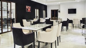 Una sala de conferencias moderna con una mesa larga, sillas blancas y negras, y un espejo grande en la pared.