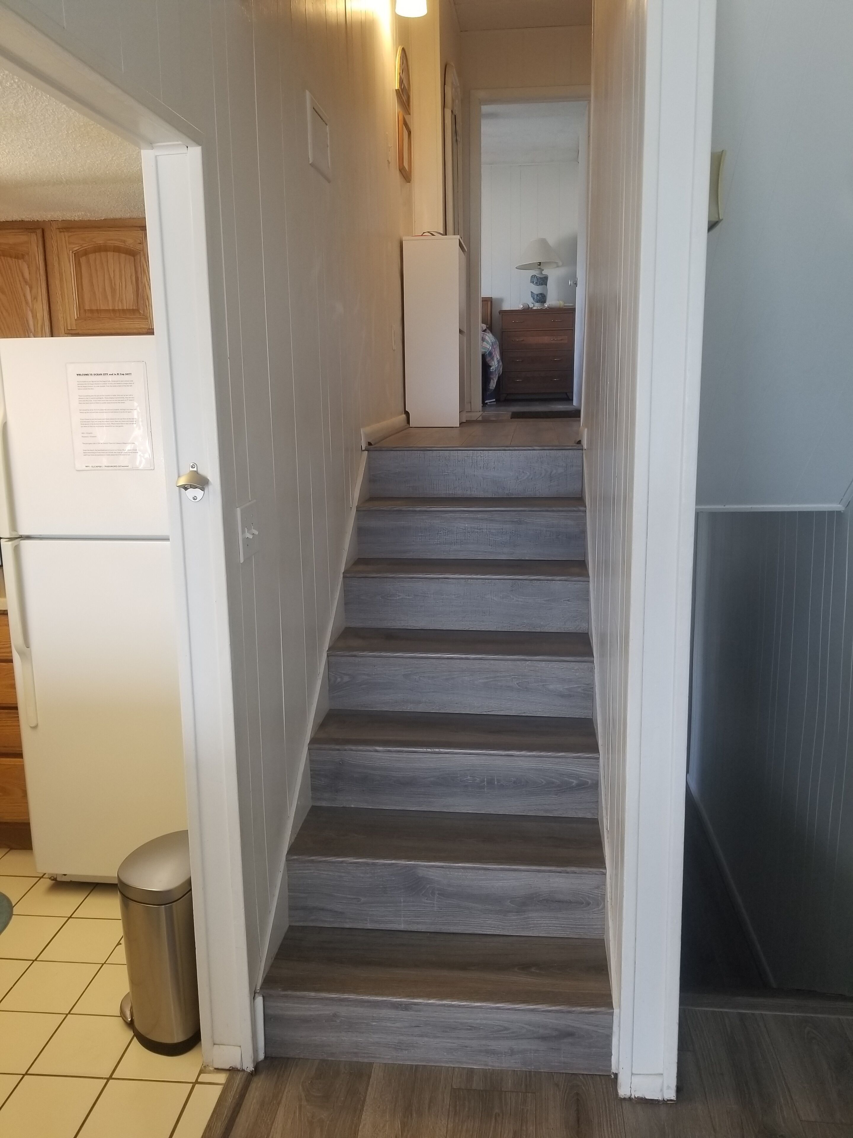Una escalera conduce a un segundo piso, donde se ve un área de cocina al fondo.