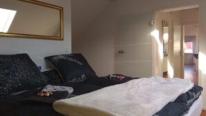Une chambre à coucher avec un lit, un grand miroir et une porte donnant sur une salle de bain.
