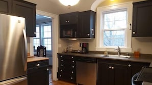 A modern kitchen with dark cabinetry, stainless steel appliances, and a wooden floor. - 1930's Gingerbread Style - Ambience & Waterviews (Armdale)