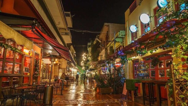 Eine schmale Straße mit Geschäften und Restaurants, beleuchtet durch warmes Licht.