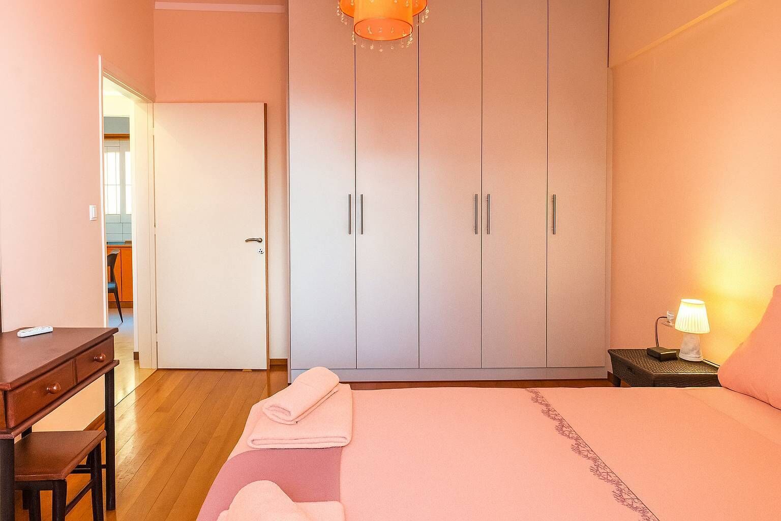 Une chambre à coucher comprenant un lit, une armoire, un bureau et une table de chevet avec une lampe.