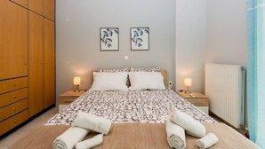 A hotel room with a bed, two bedside tables, a wardrobe, and two wall-mounted pictures.