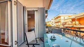 A balcony with a glass table, two chairs, and a view of neighboring buildings. - Upscale Modern Escape in the Historic Center (Kalamata)