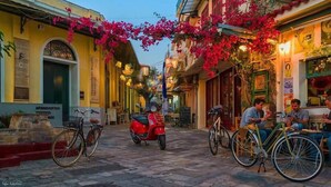 A narrow street with buildings on either side, a red scooter parked in the middle, and a bicycle to the right. - Upscale Modern Escape in the Historic Center (Kalamata)