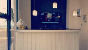 A reception area with a TV screen, hanging pendant lights, and a decorative vase. - The Key Boutique Hotel (Lomé)