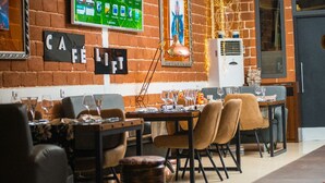 A cozy restaurant with brick walls, a TV screen, and a sign that reads "CAFE". - The Key Boutique Hotel (Lomé)