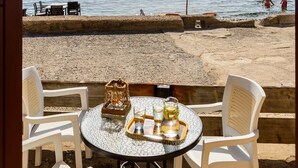 A beachside table with chairs and a table umbrella overlooking the sea. - Waveside Sanctuary - Luxurious Seastone Villa (Avia)