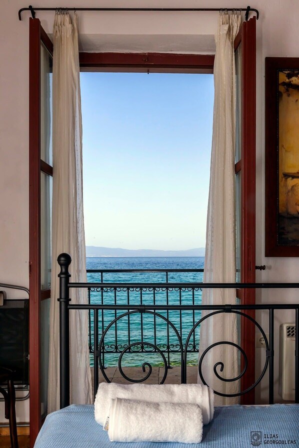 Une chambre avec un lit, une vue sur la mer et un tableau au mur.