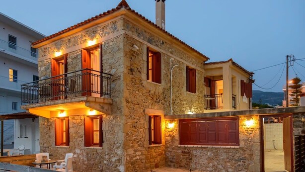 A stone building with a balcony, wooden shutters, and outdoor seating. - Waveside Sanctuary - Luxurious Seastone Villa (Avia)