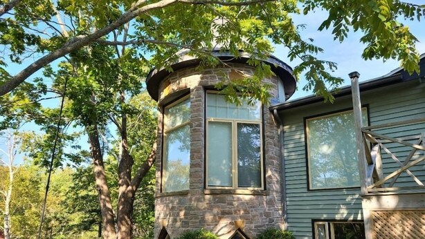A stone tower with large windows, surrounded by trees and a stone pathway.