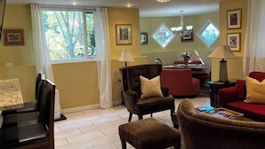 A living room with a dining area, featuring a chandelier, red sofa, and a dining table with chairs.