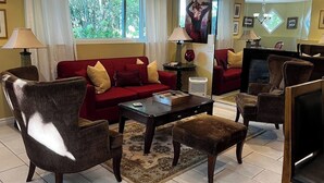 A living room with a red sofa, brown armchairs, a coffee table, and a TV.