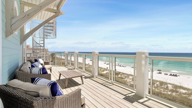Eine Holzterrasse mit Korbmöbeln und Blick auf den Strand.