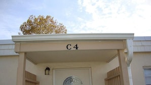 A building entrance with a sign 'C4' above the door, a small window with a glass design, and a wall-mounted light fixture. - Horizon South 12C4: 1 BR / 1 BA condo in Panama City Beach, Sleeps 4 (Panama City Beach)