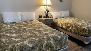 Una habitación de hotel con dos camas, una mesita de noche, una lámpara y decoración mural.