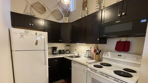 Una cocina compacta con armarios oscuros, un refrigerador blanco, una estufa y un lavamanos.