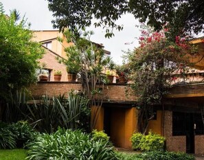 Une cour avec un bâtiment en briques, une végétation luxuriante et un petit jardin.