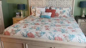 A bedroom with a bed, a ceiling fan, a green wall, and a decorative seahorse.