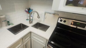 A kitchen with two sinks, a stove, and a microwave.