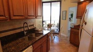 Una cocina con encimeras de granito, armarios de madera, lavavajillas y refrigerador.