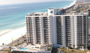 A high-rise hotel with multiple balconies, a pool area, and a beach view. - Extra large studio condominium located at Surfside Resort (Miramar Beach)